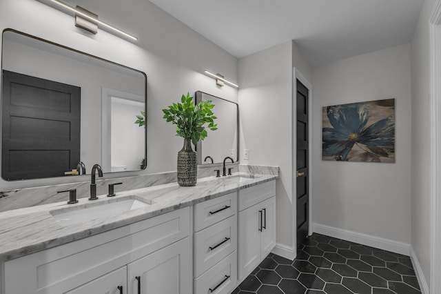 full bath with a sink, baseboards, double vanity, and tile patterned flooring