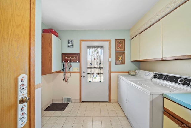 laundry area featuring light tile patterned floors, washing machine and dryer, cabinet space, and visible vents