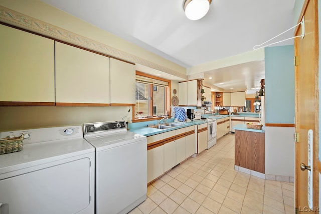 washroom with a sink, light tile patterned floors, and washer and clothes dryer