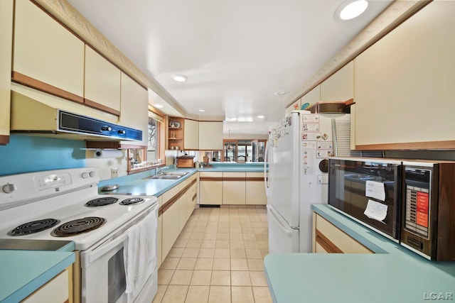 kitchen with light tile patterned flooring, a peninsula, under cabinet range hood, recessed lighting, and white appliances
