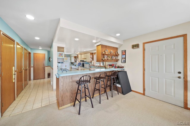 kitchen featuring open shelves, a peninsula, recessed lighting, light carpet, and a kitchen bar