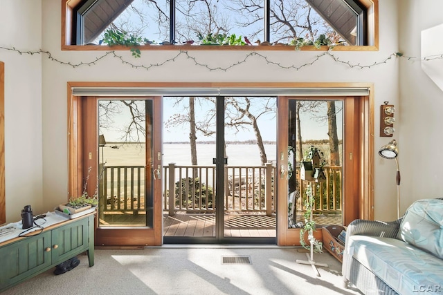 doorway to outside with visible vents, carpet, a water view, and a wealth of natural light