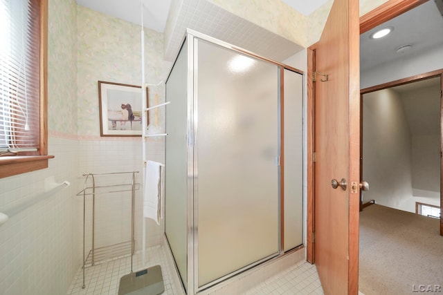 full bath featuring tile patterned flooring, tile walls, a wainscoted wall, and a shower stall