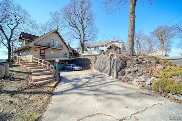 view of home's exterior featuring stairs, concrete driveway, a porch, and fence