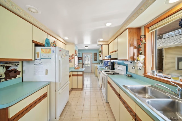 kitchen with a sink, light tile patterned flooring, under cabinet range hood, recessed lighting, and white appliances