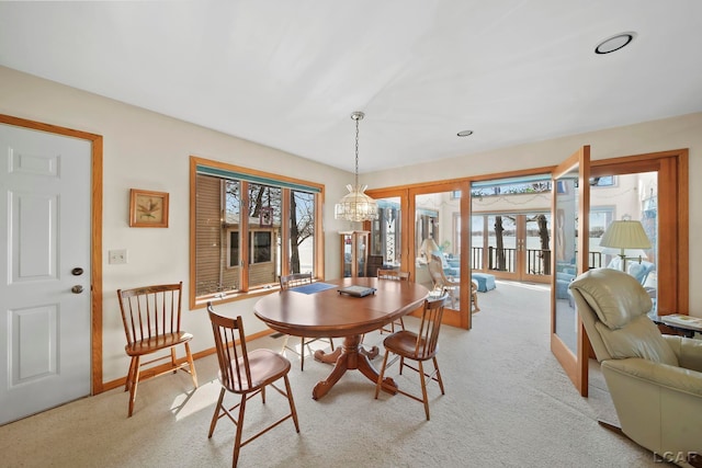 carpeted dining area with baseboards and a chandelier