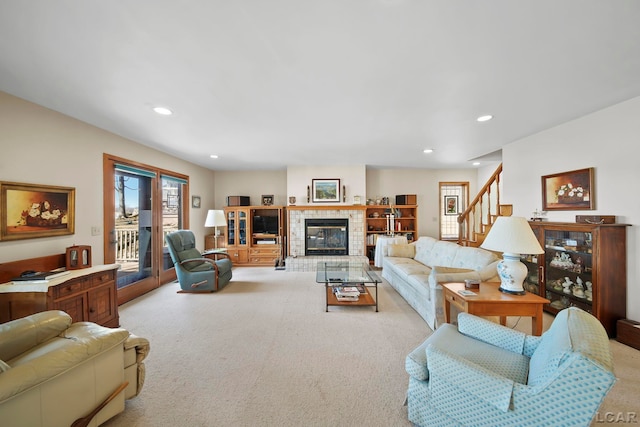 living area with a tiled fireplace, recessed lighting, stairs, and carpet floors