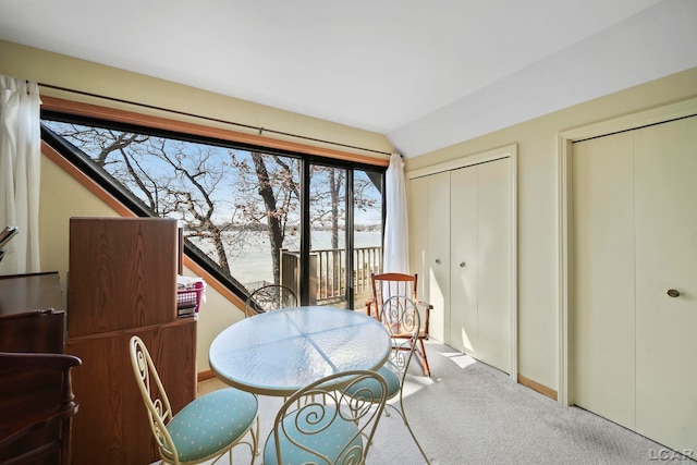 carpeted dining space featuring lofted ceiling