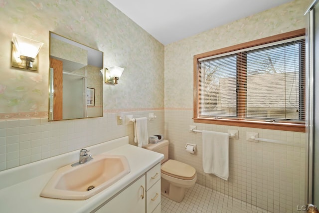 full bath with tile patterned flooring, vanity, wallpapered walls, a wainscoted wall, and a shower stall