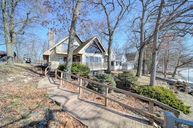 rear view of property featuring a balcony and a chimney