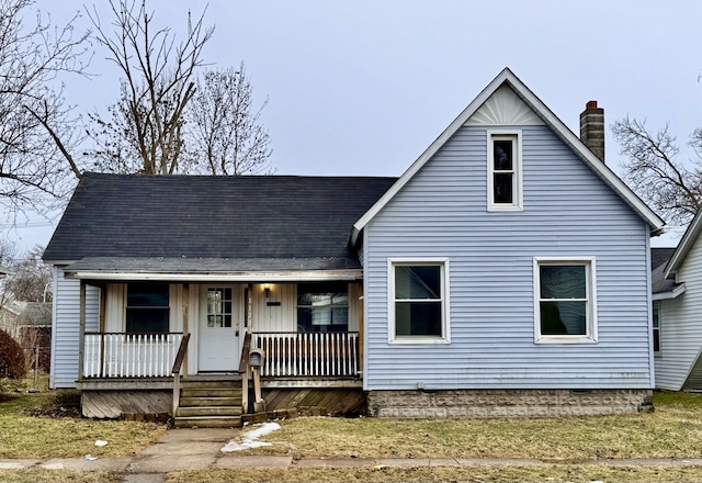 view of front facade featuring covered porch, a chimney, and a shingled roof