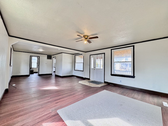 empty room with ceiling fan, a textured ceiling, dark wood finished floors, and ornamental molding