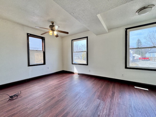 unfurnished room with baseboards, dark wood-type flooring, a ceiling fan, and a textured ceiling