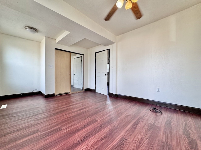 spare room with dark wood-type flooring, baseboards, and ceiling fan