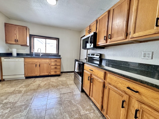 kitchen featuring brown cabinets, a sink, a textured ceiling, appliances with stainless steel finishes, and baseboards