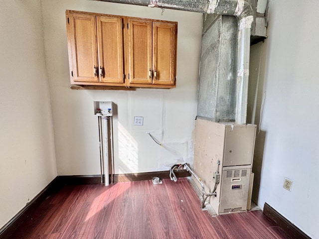 laundry area with dark wood-style floors, cabinet space, and baseboards