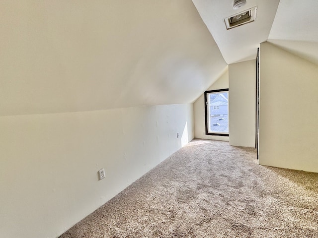 additional living space featuring visible vents, lofted ceiling, and carpet flooring