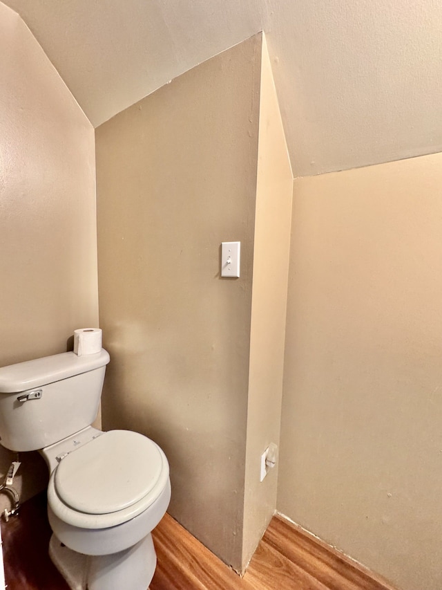 bathroom featuring toilet, wood finished floors, and vaulted ceiling