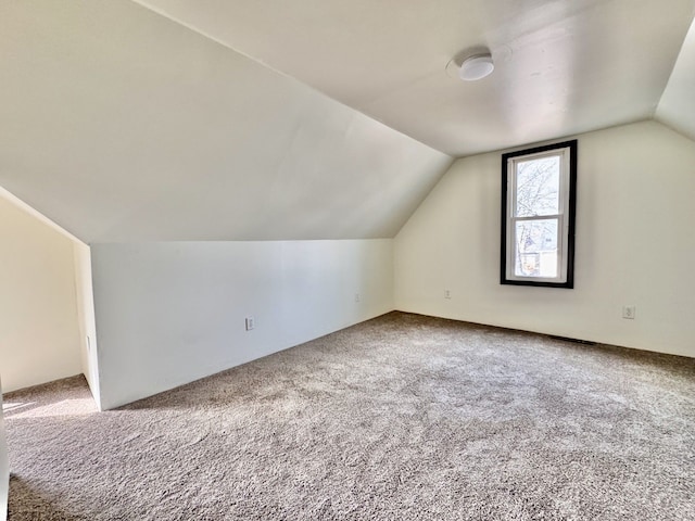 bonus room with vaulted ceiling and carpet flooring