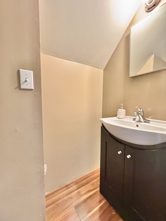 bathroom with vanity, vaulted ceiling, and wood finished floors