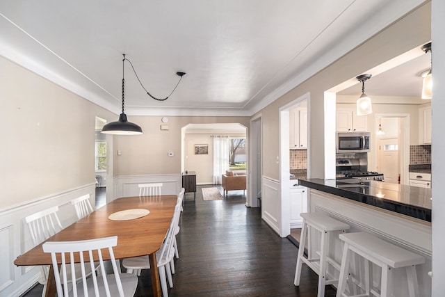 3018 Guilford Dr, Royal Oak, MI 48073 - dining room with plenty of natural light, arched walkways, a decorative wall, wainscoting, and dark wood-type flooring