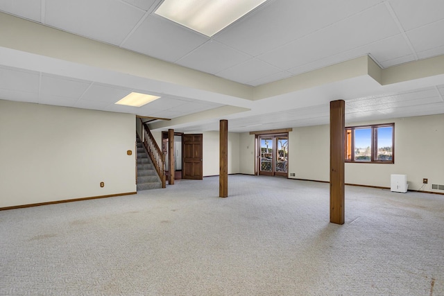 below grade area featuring visible vents, carpet floors, a paneled ceiling, baseboards, and stairs