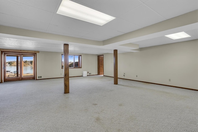 basement featuring baseboards, a paneled ceiling, and light colored carpet