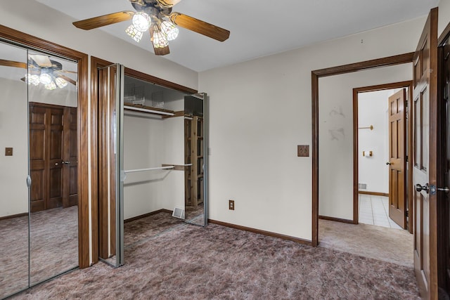 unfurnished bedroom with two closets, baseboards, carpet, and a ceiling fan