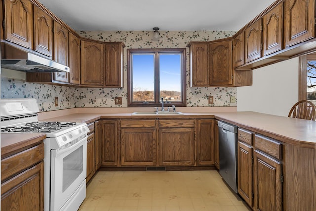 kitchen with wallpapered walls, white range with gas stovetop, and a sink