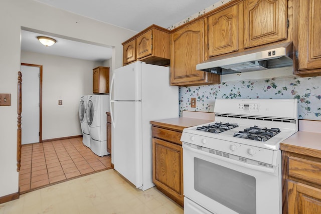 kitchen featuring under cabinet range hood, washer and clothes dryer, light countertops, brown cabinetry, and white appliances