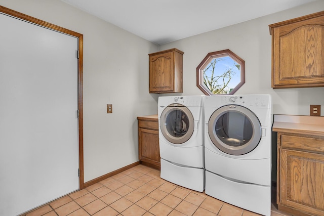 laundry area with light tile patterned floors, baseboards, cabinet space, and washing machine and clothes dryer