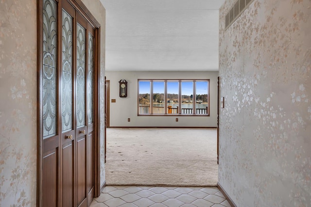 entryway featuring baseboards, visible vents, and light carpet