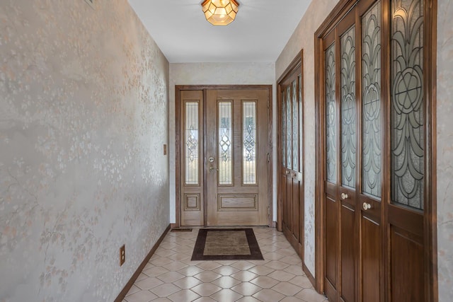 foyer featuring light tile patterned floors, baseboards, and wallpapered walls