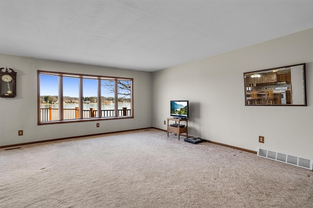 unfurnished living room with visible vents, baseboards, and carpet