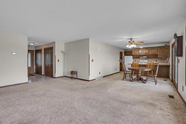 interior space featuring a ceiling fan, light colored carpet, visible vents, and baseboards