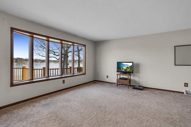 unfurnished living room with baseboards, a water view, visible vents, and carpet flooring