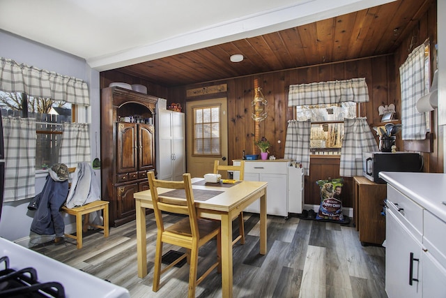 dining space featuring wooden walls, wooden ceiling, and wood finished floors