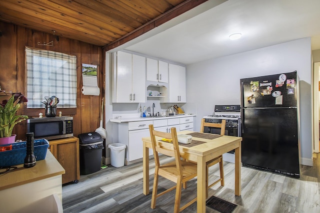 kitchen with stainless steel microwave, gas range, light countertops, freestanding refrigerator, and a sink