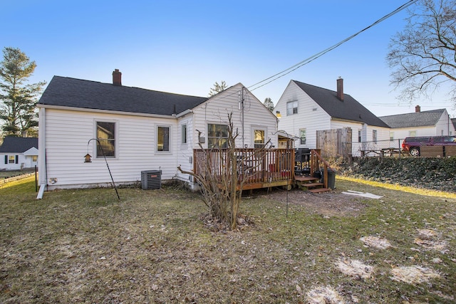 rear view of property featuring central air condition unit, a lawn, fence, a wooden deck, and a chimney