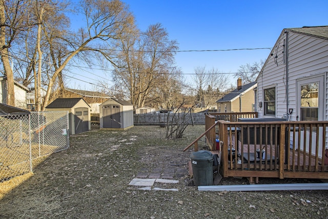 view of yard with a storage unit, a fenced backyard, an outbuilding, and a deck