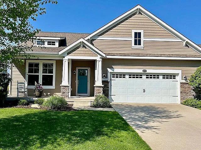 craftsman-style home with a front yard, stone siding, and driveway