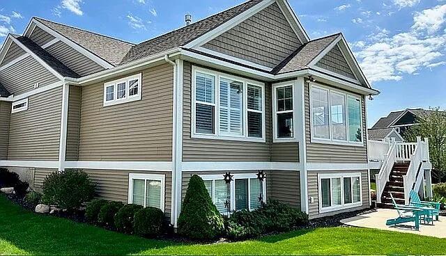 view of side of home featuring a lawn, a deck, a patio, a sunroom, and stairs