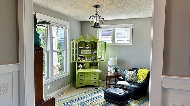 living area featuring visible vents, baseboards, a textured ceiling, and an inviting chandelier