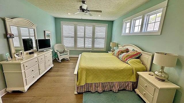 bedroom featuring dark wood finished floors, ceiling fan, baseboards, and a textured ceiling