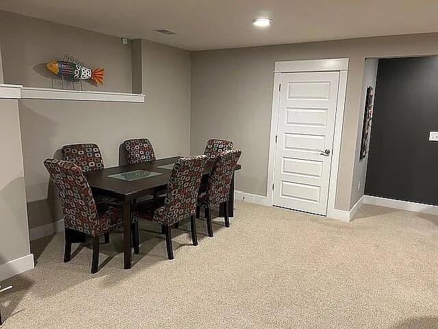 dining space featuring light carpet, visible vents, and baseboards