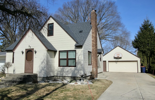 view of front of property featuring an outbuilding, a front yard, a shingled roof, a garage, and a chimney