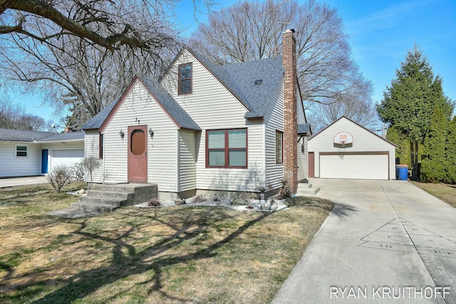 view of front facade with a front lawn, a detached garage, roof with shingles, an outdoor structure, and a chimney