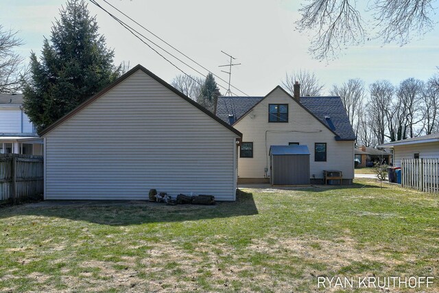 rear view of house with a lawn and fence