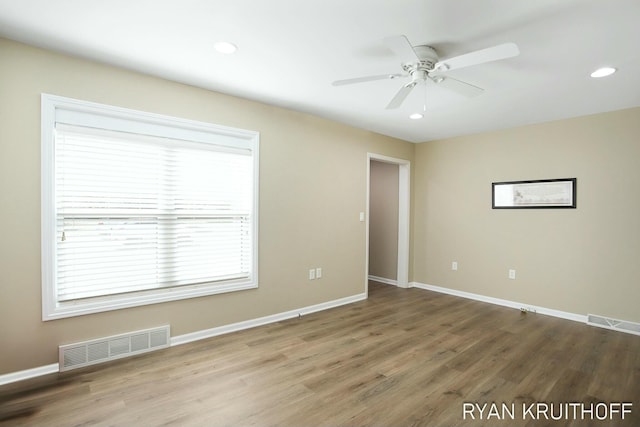 empty room featuring wood finished floors, baseboards, and visible vents