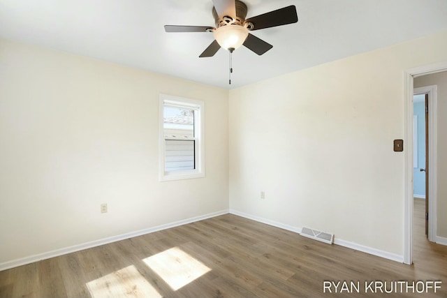 empty room with ceiling fan, visible vents, baseboards, and wood finished floors